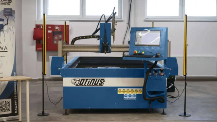 Otinus CNC cutting table with touchscreen control panel, safety light curtains, and gantry system, set up in an industrial workshop.