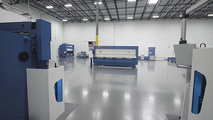 Spacious industrial showroom with metalworking machines arranged on a polished factory floor, showcasing a clean, modern production environment.